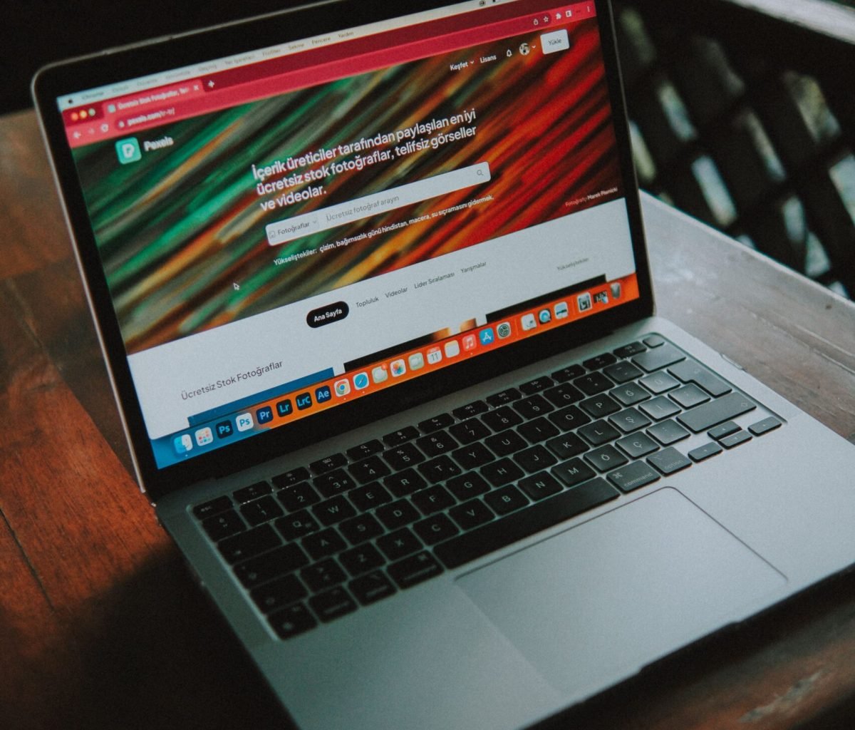 A close-up view of a laptop with a website open, placed on a wooden table near a window.